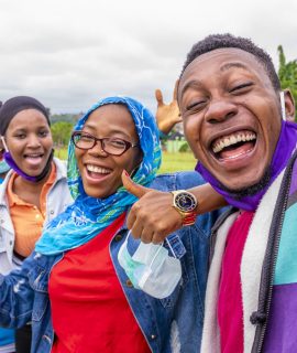 A group of cheerful African friends with facemasks taking a selfie in a park