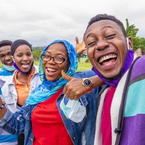 A group of cheerful African friends with facemasks taking a selfie in a park