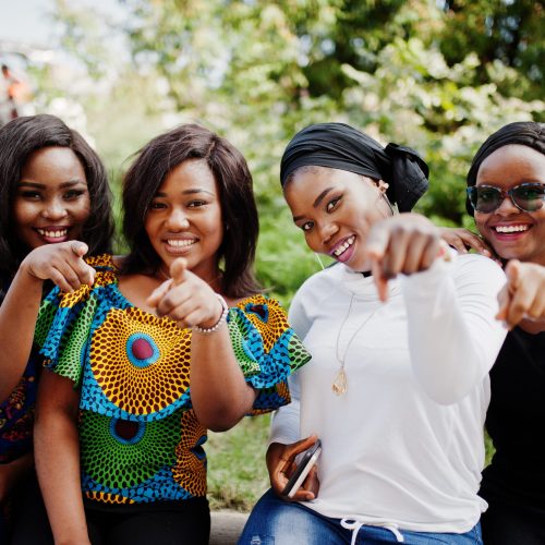 Group of four african american girls sitting outdoor and showing fingers.